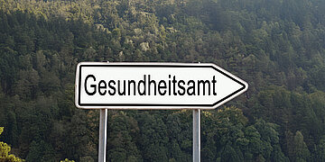 Foto: Ein wei&szlig;es Stra&szlig;enschild zeigt nach rechts, darauf der Schriftzug "Gesundheitsamt".