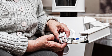 Ein Roboter h&auml;lt die Hand einer Seniorin.