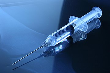 Injektionsspritze Eine medizinische Injektionsspritze vor einem blauen Hintergrund.