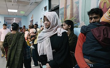 Im Krankenhausflur ist eine lange Schlange von Eltern mit Kindern, die auf die Behandlung warten.