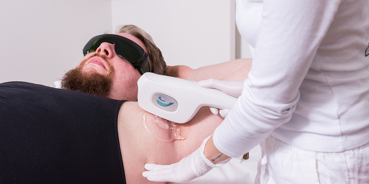 Das Foto zeigt einen Mann, der mit Licht und Radiofrequenz gegen Akne inversa behandelt wird.