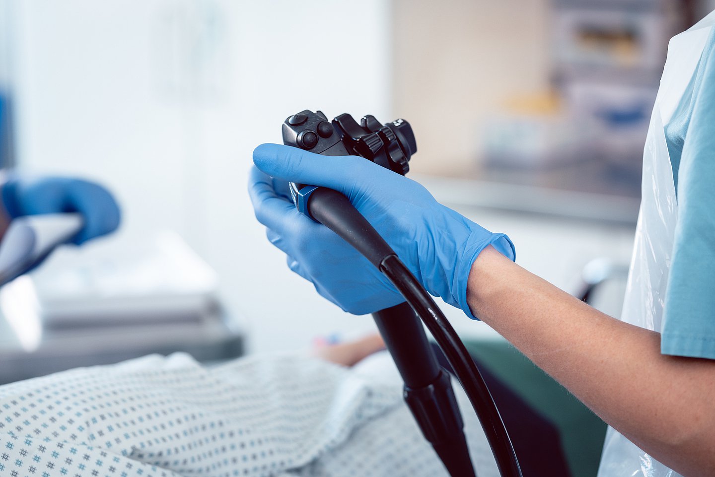 Foto zeigt das Steuerelement des Koloskop in der Hand eines Arztes während der Darmspiegelung eines narkotisierten Patienten.