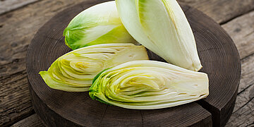 Chicro&eacute;e liegt auf einem Holzteller auf einem Holztisch