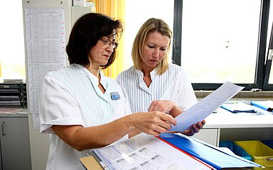 Zwei Pflegerinnen tauschen sich aus.