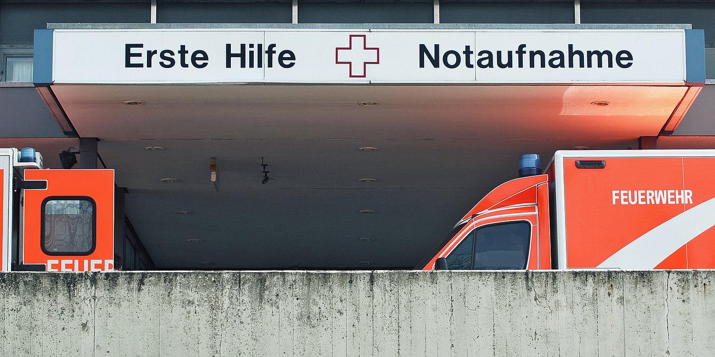 Der Eingang zur Notaufnahme: Zwei Rettungsfahrzeuge stehen vor dem Einfang. Über dem Eingang steht auf dem Schild "Erste Hilfe" und "Notaufnahme".
