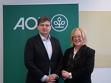 Die Vorstandsvorsitzende der AOK Bayern, Dr. Irmgard Stippler, und der BH&Auml;V-Vorsitzende Dr. Wolfgang Ritter stehen vor einem AOK-Banner.