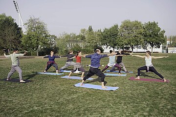 Eine Gruppe betreibt unter Anleitung Gesundheitssport im Freien