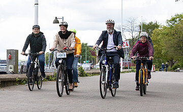 An der Kiellinie radeln Landes-Verkehrsminister Claus Ruhe Madsen (rechts) und AOK-Landesdirektorin Iris Kr&ouml;ner (links) mit Besch&auml;ftigten des Landes-Verkehrsministeriums.
