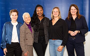 F&uuml;nf Frauen stehen nebeneinander vor blauem Hintergrund.