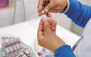 Die Hände einer Frau: Sie hält ein Fläschen Impfdosis in der Hand.