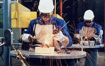 schweißen Zwei junge Männer bei Schweißerarbeiten in einer Werkstatt