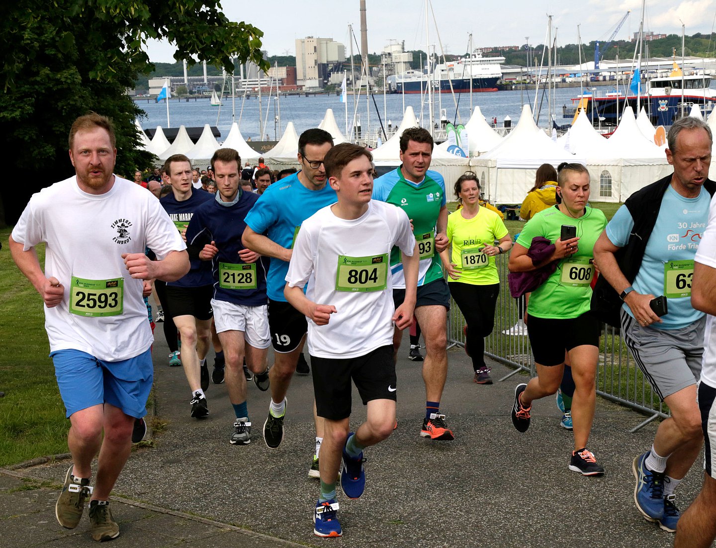 Foto zeigt viele Läufer, die in Höhe Reventlouwiese auf der 4,5 Kilometer langen Laufstrecke des AOK-Business.Run Kiel unterwegs sind. Im Hintergrund ist die Kieler Förde zu sehen.