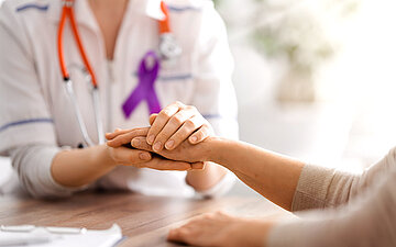Eine &Auml;rztin h&auml;lt der Patientin im Gespr&auml;ch die Hand.