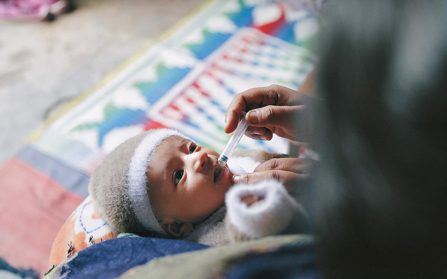 Eine Frau gibt einem kleinen Baby die Impftropfen.
