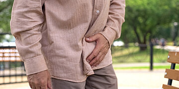 Ein Mann im Park hält sich die Leiste.