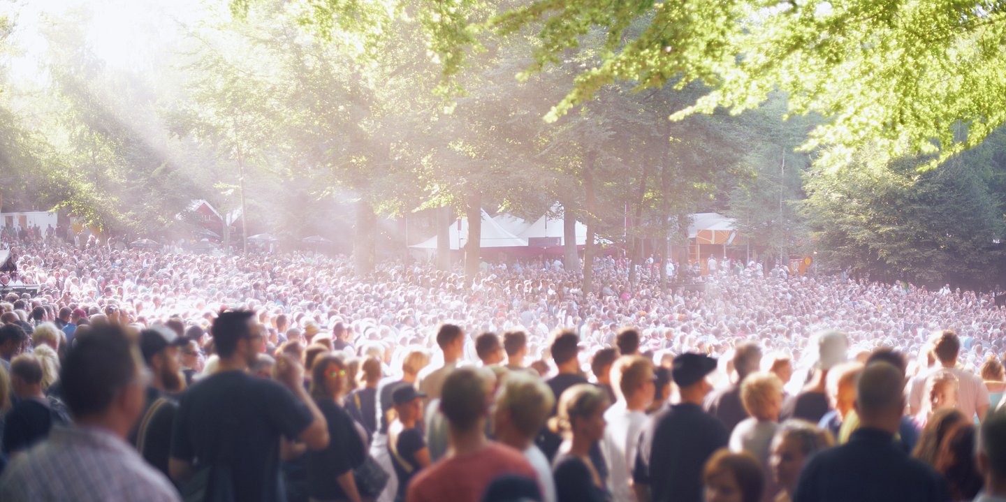 Das Bild zeigt mehrere Tausend Zuschauer in einer Freiluft-Arena, die intensiver Sonneneinstrahlung ausgesetzt ist.