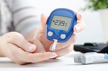 Antidiabetika in Westfalen-Lippe Nahaufnahme der Hände einer Frau, die mit einem Bluttropfen den Blutzuckerspiegel testet.