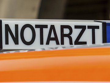 Schlaganfall Schleswig-Holstein Foto zeigt eine beleuchtbares Notarztschild (schwarze Schrift auf weißem Grund) auf einem orangefarbenen Autodach.