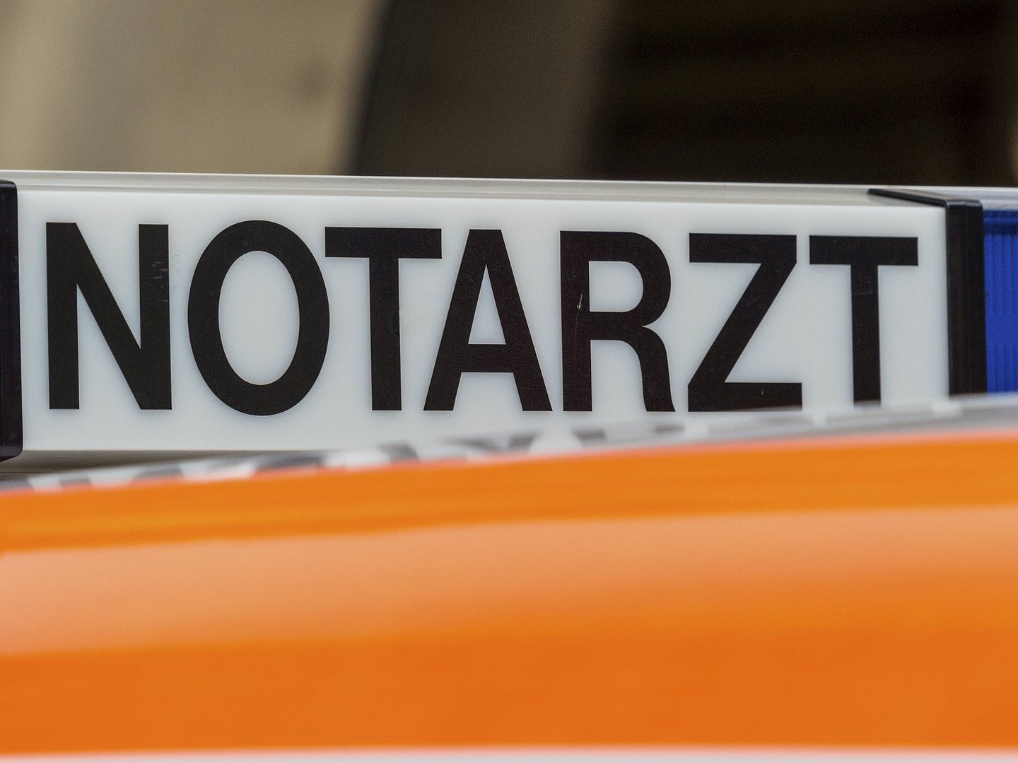 Foto zeigt eine beleuchtbares Notarztschild (schwarze Schrift auf weißem Grund) auf einem orangefarbenen  Autodach.