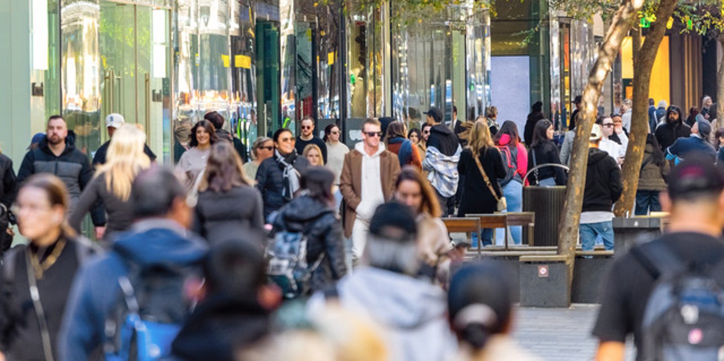 Menschen gehen durch die Fußgängerzone einer Stadt.