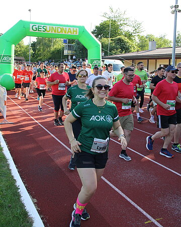 L&auml;uferinnen und L&auml;ufer starten durch ein gr&uuml;nes Tor zum AOK-Firmenlauf.