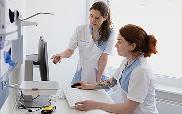Foto: Arzthelferinnen gucken auf einen Computer