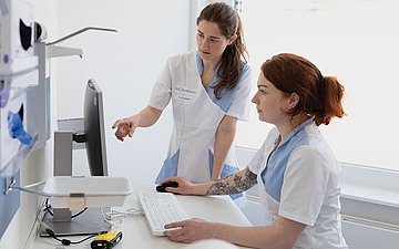 Melanie Korneck und Elena Zimmermann bei einer Fallbesprechung. Foto: Arzthelferinnen gucken auf einen Computer