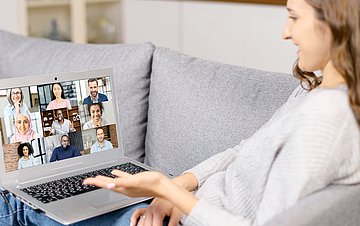 virtuelle Selbsthilfe Foto einer jungen Frau auf dem Sofa, die sich mit anderen in einer virtuellen Selbsthilfegruppe austauscht