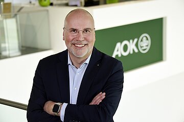 Portrait Johannes Bauernfeind vor einem AOK-Logo