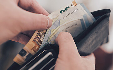 Eine Person schaut nach Geld in ihrem Portemonnaie.