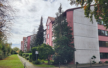 Foto: In einer begr&uuml;nten Stra&szlig;e steht ein Geb&auml;ude.
