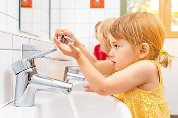 Kleine Kinder stehen im Waschraum einer KiTa und waschen sich die H&auml;nde.