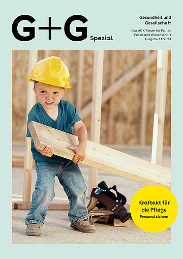 Foto: Ein kleiner Junge mit einem gelben Bauarbeiterhelm zieht eine Holzlatte.