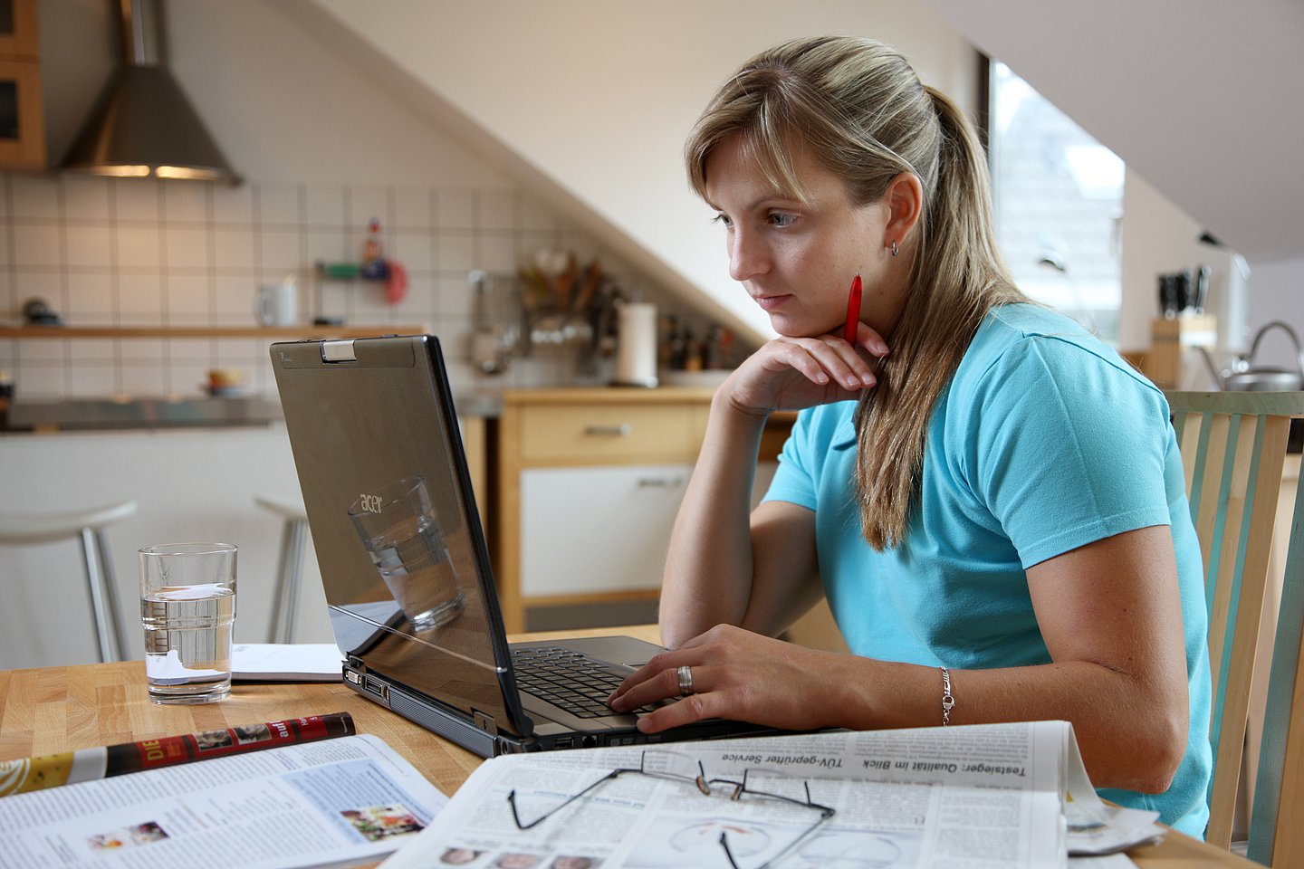Eine Frau arbeitet zu Hause. Sie sitzt am Küchentisch mit ihrem Computer.