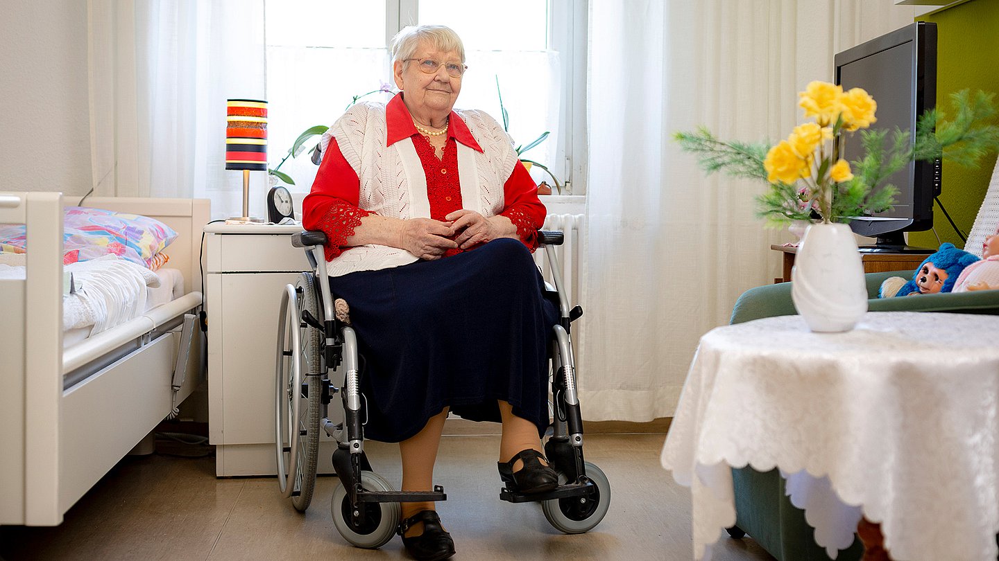 Eine Seniorin sitzt in einem Rollstuhl im Pflegeheim
