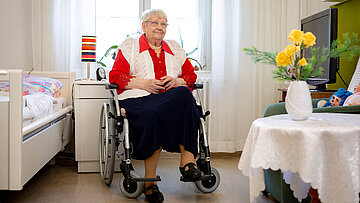 Eine Seniorin sitzt in einem Rollstuhl im Pflegeheim