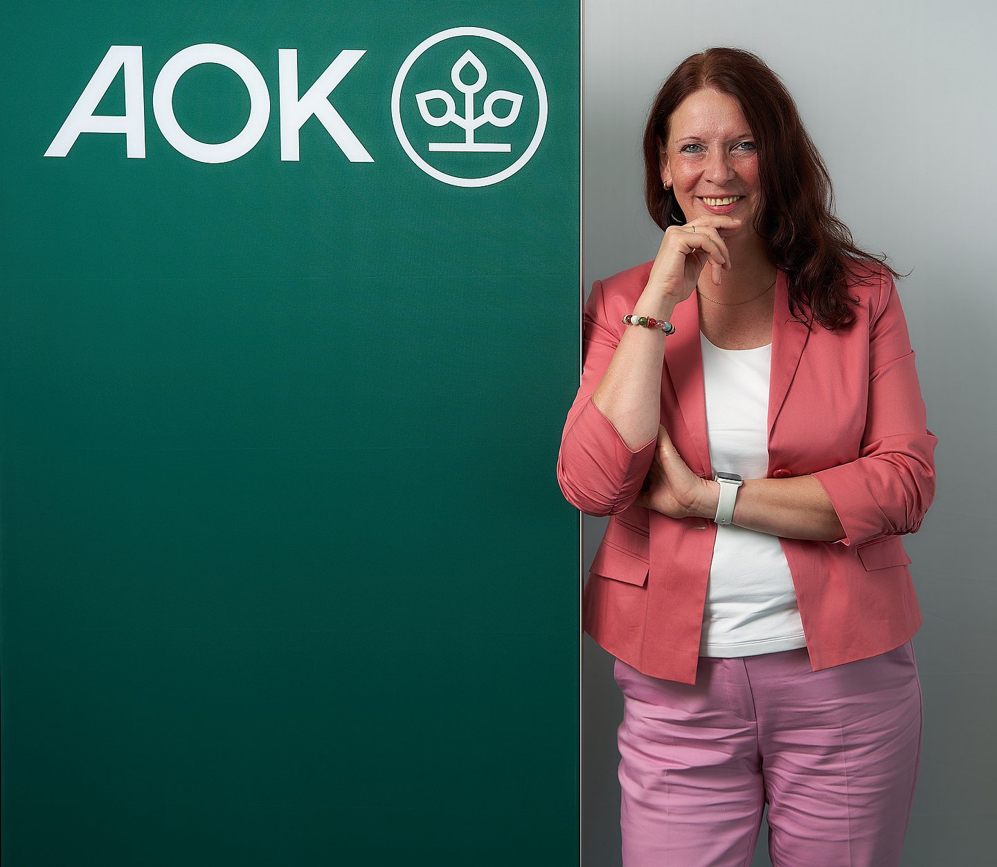 Porträtfoto: Martina Niemeyer lehnt an einem Roll-Up mit AOK-Logo