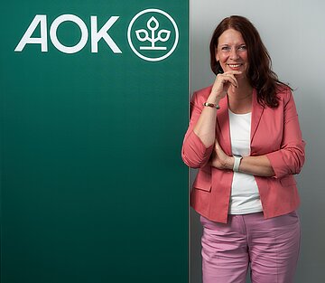 Portr&auml;tfoto: Martina Niemeyer lehnt an einem Roll-Up mit AOK-Logo