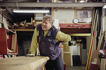 Ein Mann h&auml;lt sich den schmerzenden R&uuml;cken