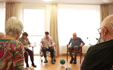 Training im Stuhlkreis: Mit Hilfe eines Balls wird die Beweglichkeit geschult.