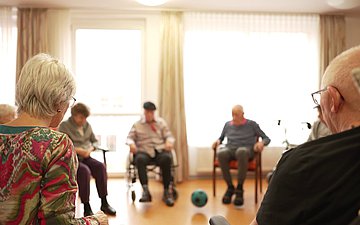 Training im Stuhlkreis: Mit Hilfe eines Balls wird die Beweglichkeit geschult.