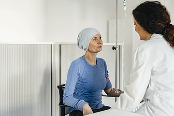 &Auml;rztin sitzt Patientin gegen&uuml;ber. Die Patientin erh&auml;lt eine Infusion
