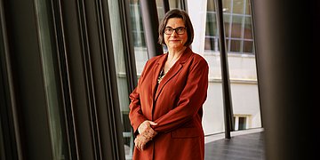 Foto: Christine Fuchsloch, Präsidentin des Bundessozialgerichtes (BSG), steht auf einem Gang vor einer Fensterfront.