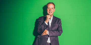 Der baden-w&uuml;rttembergische Gesundheitsminister vor einem Greenscreen.
