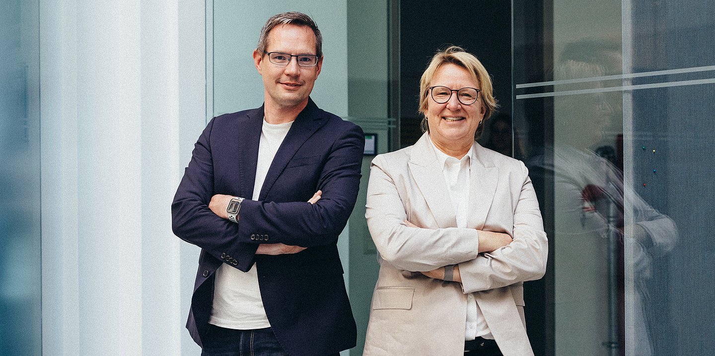 Foto von Kornell Adolph und Sylvia Thun, die sie beide mit verschränkten Armen nebeneinander stehen