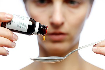 Dosierung von Arzneimitteln Eine junge Frau zählt die Tropfen eines Medikaments.