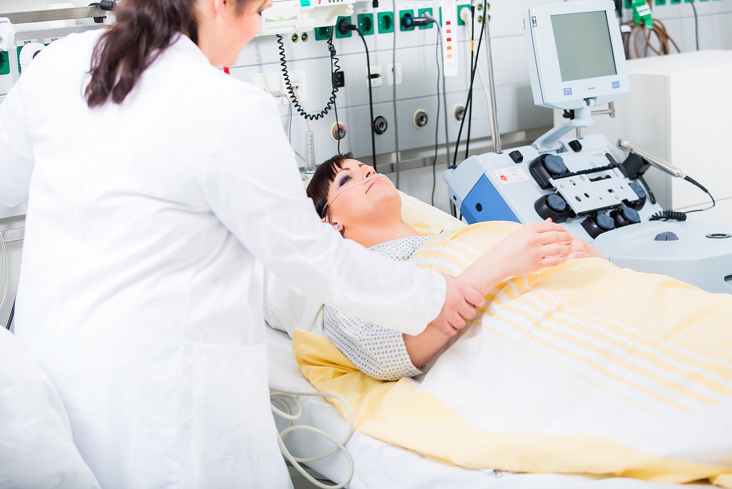 Eine Patientin liegt in einem Behandlungsraum und wird vom medizinischen Personal für einen Eingriff oder eine Behandlung vorbereitet.