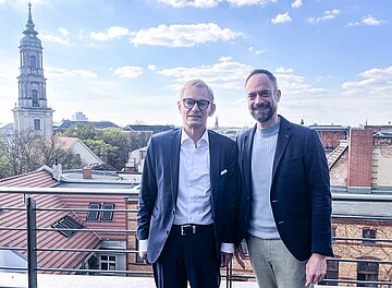 Die gew&auml;hlten Personen stehen auf der Berliner Dachterrasse mit der Stadtkulisse im Hintergrund. 