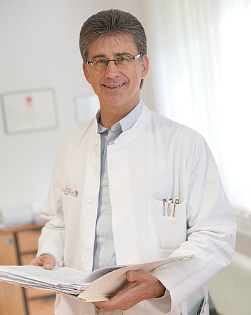 Porträt von Prof. Dr. Heinz Völler Porträt von Prof. Dr. Heinz Völler im weißen Kittel in einem hellen Raum