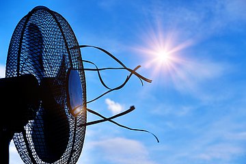 Ventilator Symbolbild Hitze: Ventilator vor der Sonne am blauen Himmel